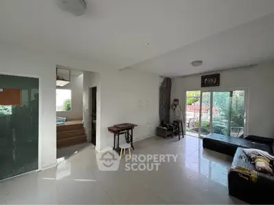 Spacious living room with natural light and garden view, featuring modern furniture and open layout.