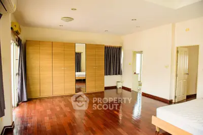 Spacious bedroom with wooden flooring and large wardrobe