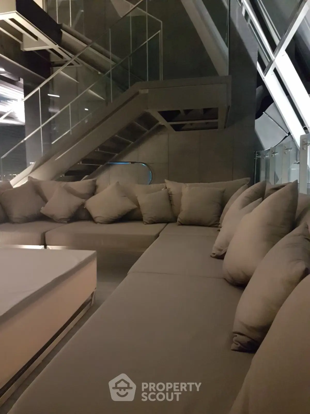 Luxurious modern living room with sleek design and plush seating under a stylish staircase.
