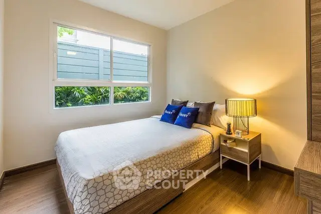 Cozy bedroom with modern decor and large window offering natural light