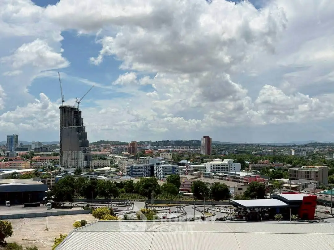 Panoramic cityscape view with construction site and urban skyline under a cloudy sky.