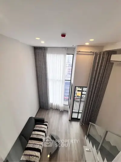 Modern loft-style living room with high ceilings and large windows