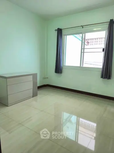 Spacious empty bedroom with tiled floor and natural light