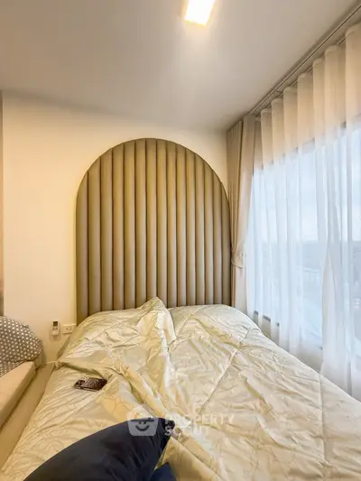 Modern bedroom with stylish headboard and large window offering city views.