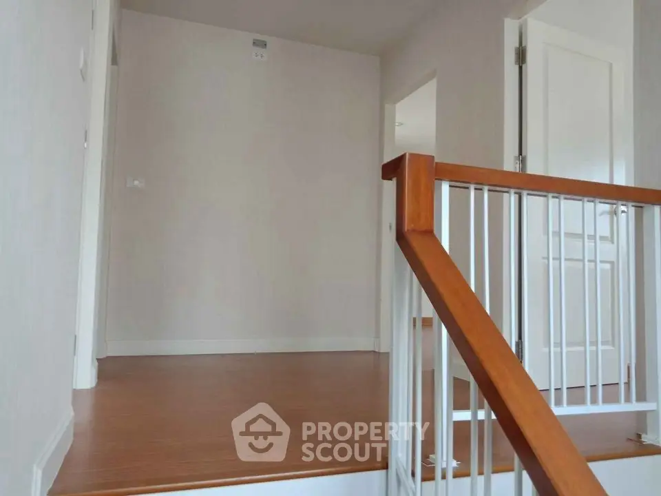 Spacious hallway with wooden flooring and modern railing, ideal for elegant home design.