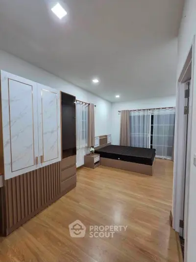 Spacious bedroom with modern design and wooden flooring, featuring large windows for natural light.