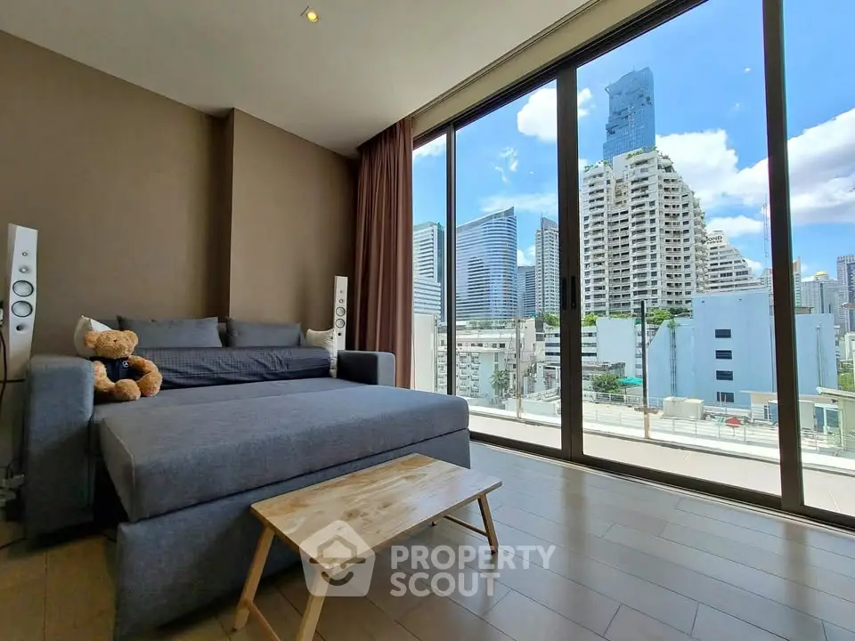 Modern living room with large windows offering stunning cityscape views, featuring a cozy sofa and wooden coffee table.
