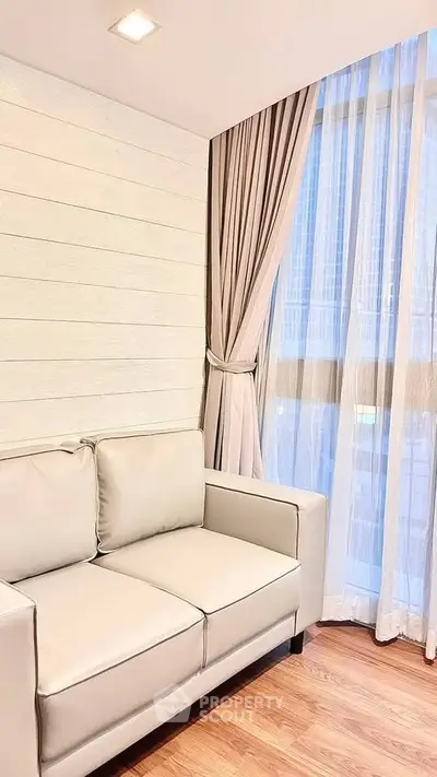 Modern living room with elegant sofa and large window with curtains, showcasing a cozy and inviting atmosphere.