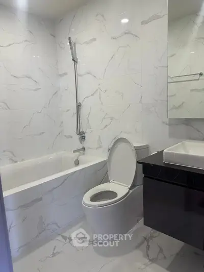 Modern bathroom with marble tiles, bathtub, and sleek fixtures.