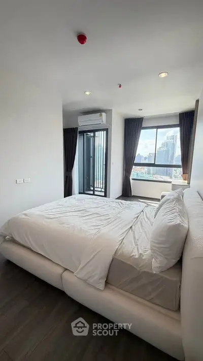 Modern bedroom with city view and balcony access in high-rise apartment