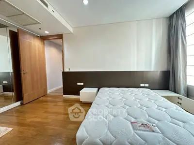 Spacious bedroom with wooden flooring and modern design in a luxury apartment.