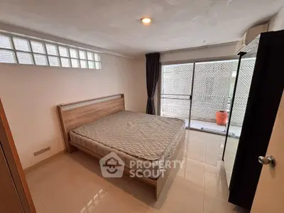 Spacious bedroom with large window and modern decor in a stylish apartment.