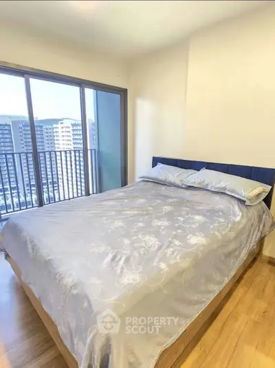 Modern bedroom with large window offering stunning city view in high-rise apartment.