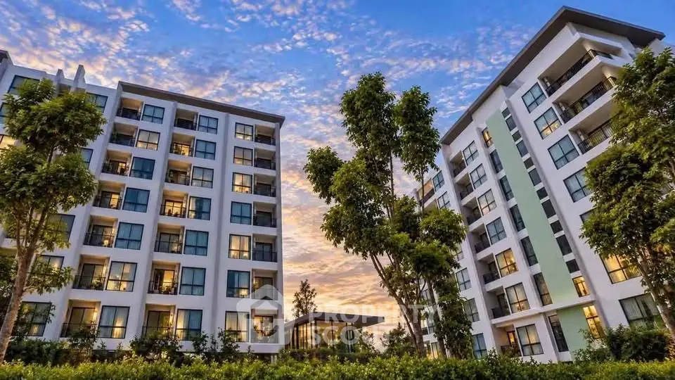 Modern apartment buildings with lush greenery and vibrant sunset sky.
