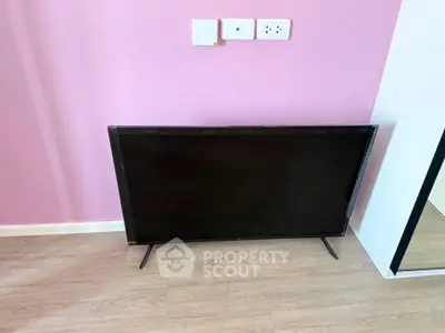 Modern interior with sleek TV against pink wall and wooden flooring