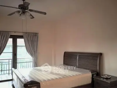 Spacious bedroom with elegant wooden bed and ceiling fan, featuring a balcony view.