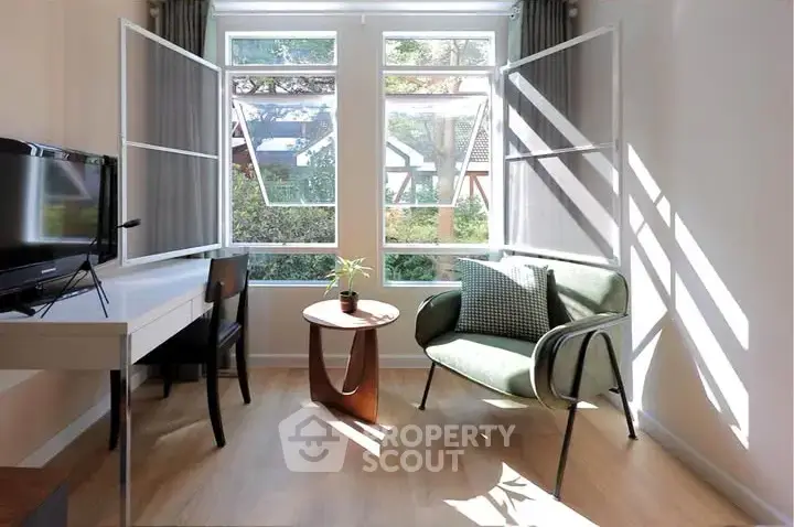 Bright living room with modern furniture and large windows offering garden views.