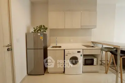 Modern kitchen with sleek appliances and minimalist design, featuring a washing machine and compact fridge.