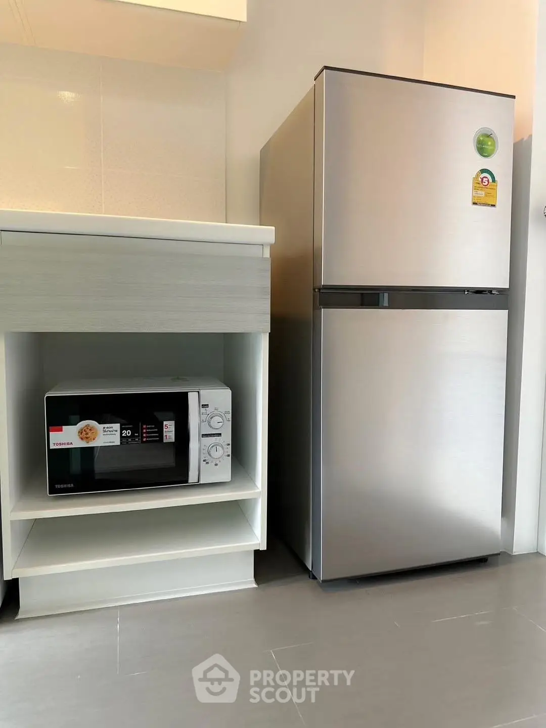 Modern kitchen with sleek fridge and microwave in compact layout.