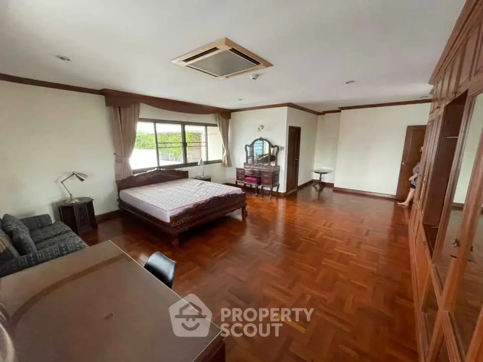 Spacious bedroom with wooden flooring and large windows in elegant home
