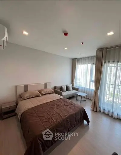 Spacious bedroom with modern decor and large windows offering natural light and city views.