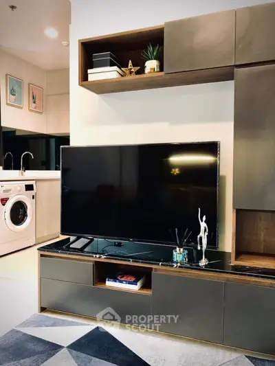 Modern living room with sleek TV unit and washer in open layout kitchen.