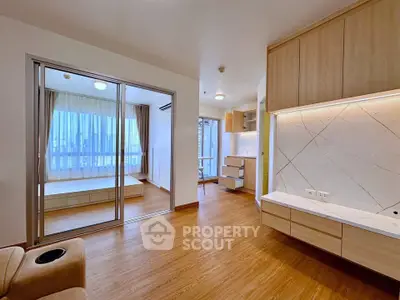 Modern apartment interior with open layout, wooden flooring, and large windows offering city views.