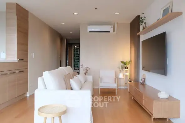 Modern living room with sleek furniture and wall-mounted TV, featuring wooden flooring and neutral tones.