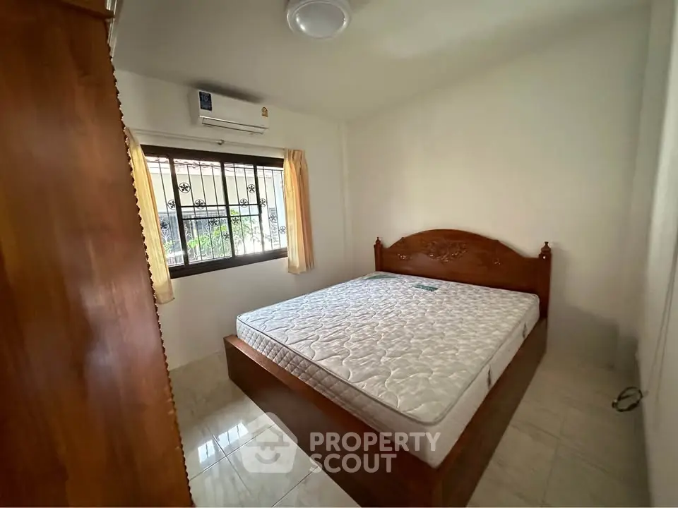 Cozy bedroom with wooden bed frame and air conditioning, perfect for restful nights.