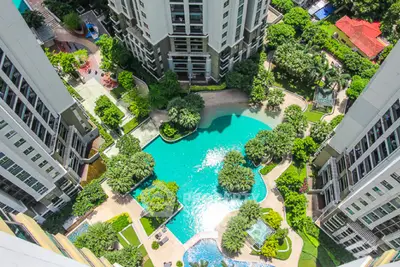 Stunning aerial view of luxury apartment complex with lush gardens and sparkling pool.