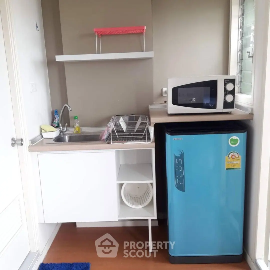 Compact kitchen with modern appliances and vibrant blue fridge