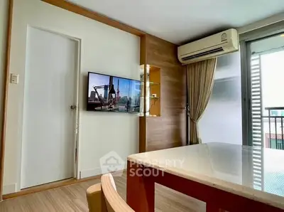 Modern living room with air conditioning and balcony access, featuring sleek wooden accents and a wall-mounted TV.