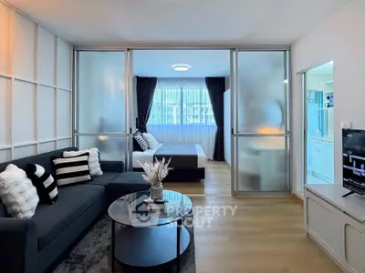 Modern studio apartment with stylish living area and bedroom separated by frosted glass sliding doors.