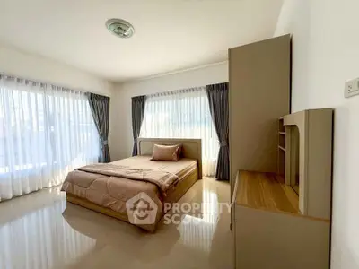 Spacious bedroom with large windows and elegant furnishings, perfect for relaxation and comfort.