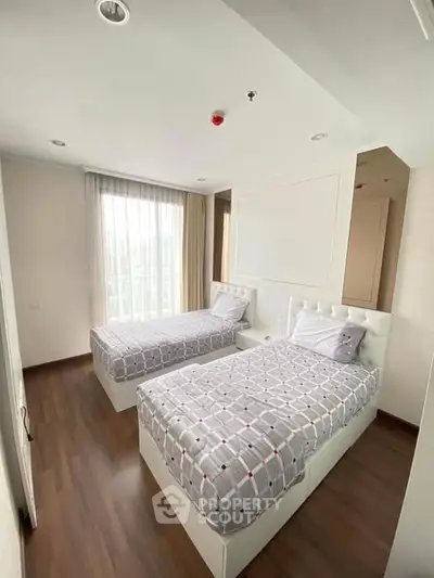 Modern bedroom with twin beds and large window offering natural light