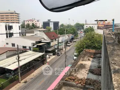 Urban street view from rooftop showcasing residential and commercial buildings with clear sky.