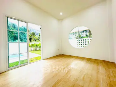 Bright and airy room with large windows and circular feature, overlooking lush greenery.