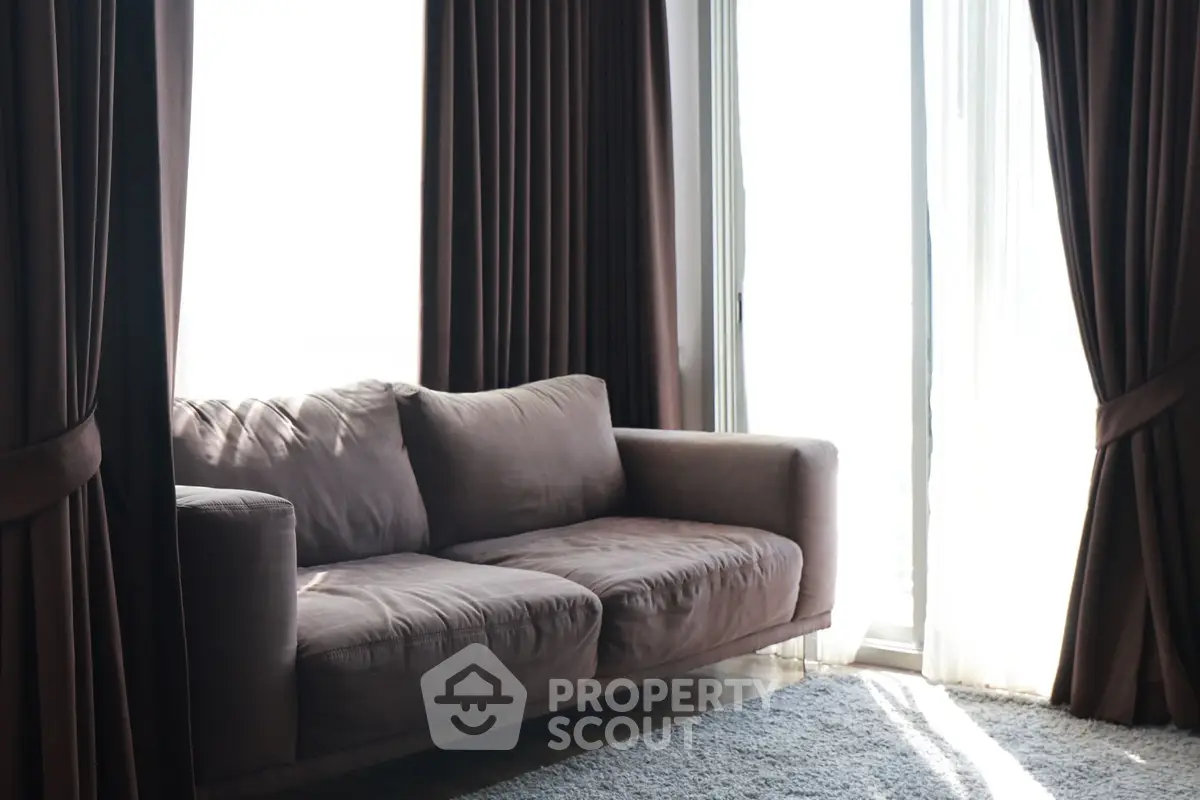 Elegant living room with plush sofa and floor-to-ceiling windows, perfect for natural light lovers.