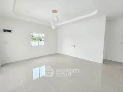 Spacious empty room with modern lighting and tiled flooring, ready for customization.