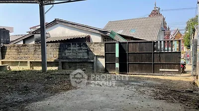Spacious outdoor area with potential for development, featuring a secure gate and surrounding buildings.
