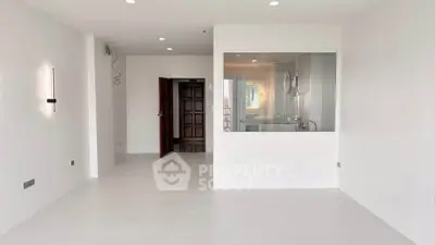 Spacious modern living room with white walls and large window, perfect for natural light.