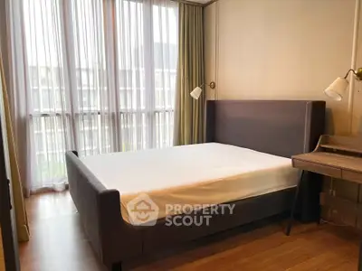 Modern bedroom with large windows and stylish furniture in a cozy apartment.