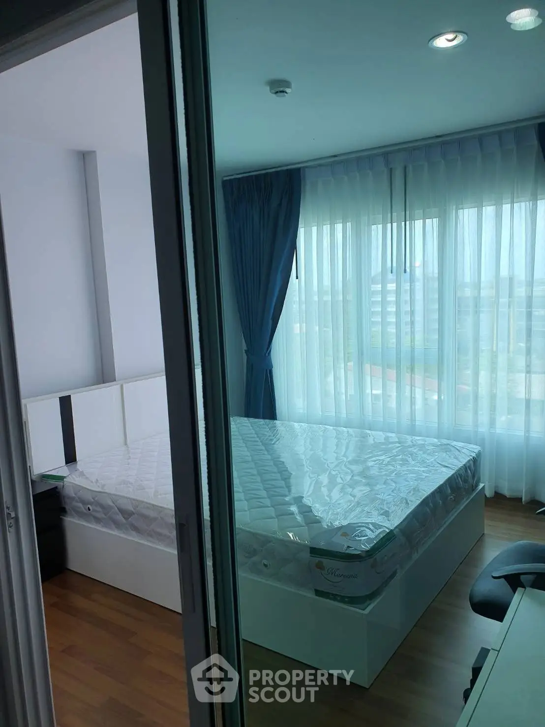 Modern bedroom with large windows and natural light, featuring a comfortable bed and stylish curtains.