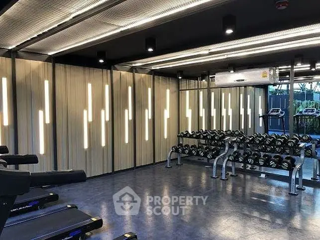 Modern gym with state-of-the-art equipment and stylish lighting in a luxury residential building.