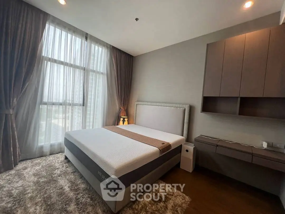 Luxurious bedroom with large window and modern furnishings in high-rise apartment