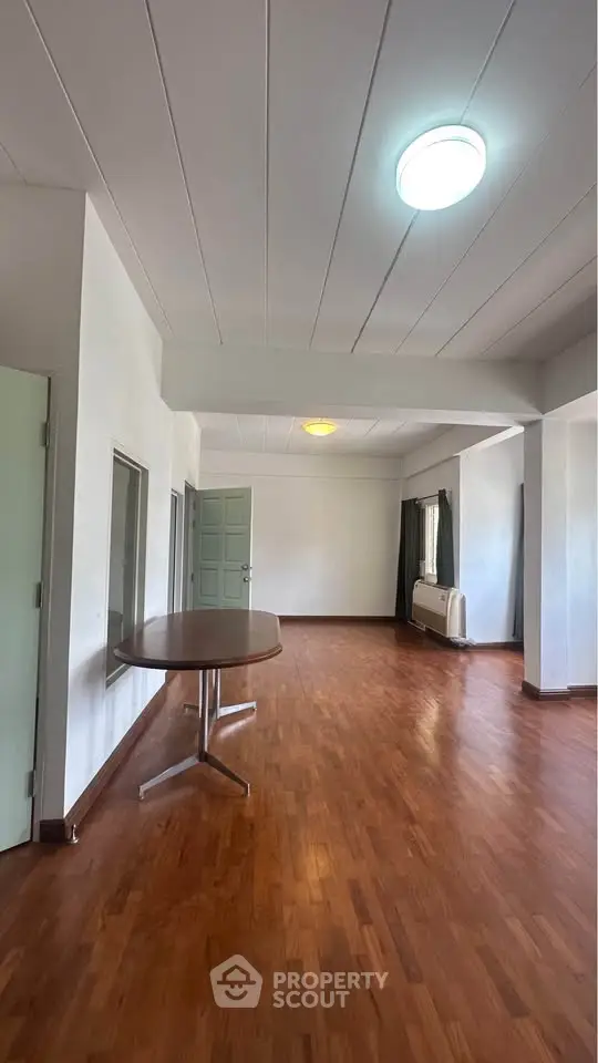 Spacious open-plan living area with wooden flooring and natural light, perfect for modern living.