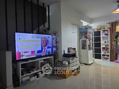 Spacious living room with modern decor and large TV, featuring sleek storage solutions and bright lighting.