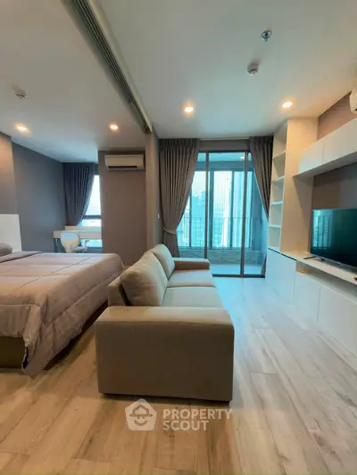 Modern studio apartment with cozy living area and city view balcony