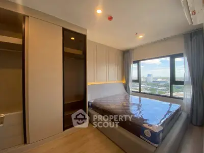 Modern bedroom with large window offering city view, featuring sleek wardrobe and cozy bed.