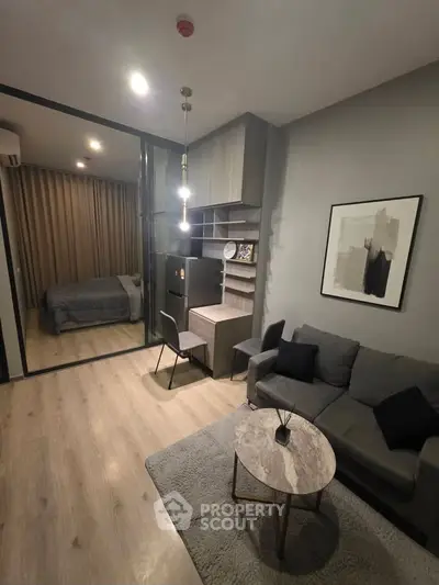 Modern living room with cozy sofa, stylish decor, and view into bedroom through glass partition.